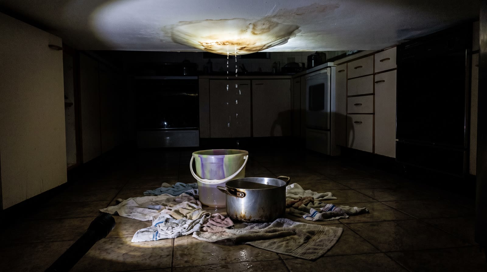 Ceiling leak dripping into a bucket at night